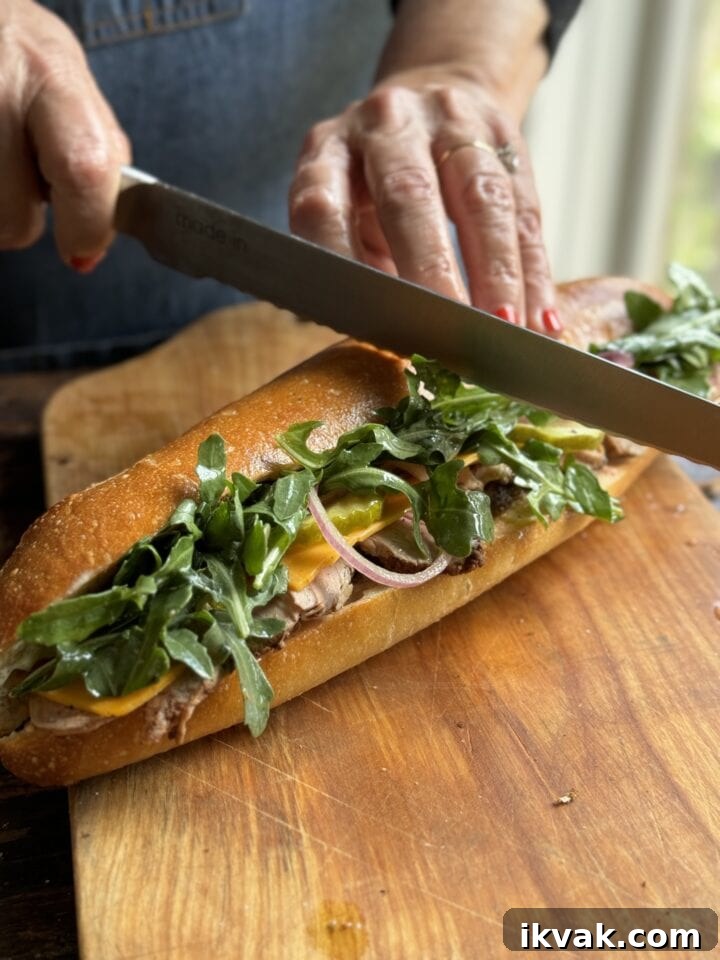 Fresh homemade sub sandwich with greens and deli meat on a wooden cutting board.