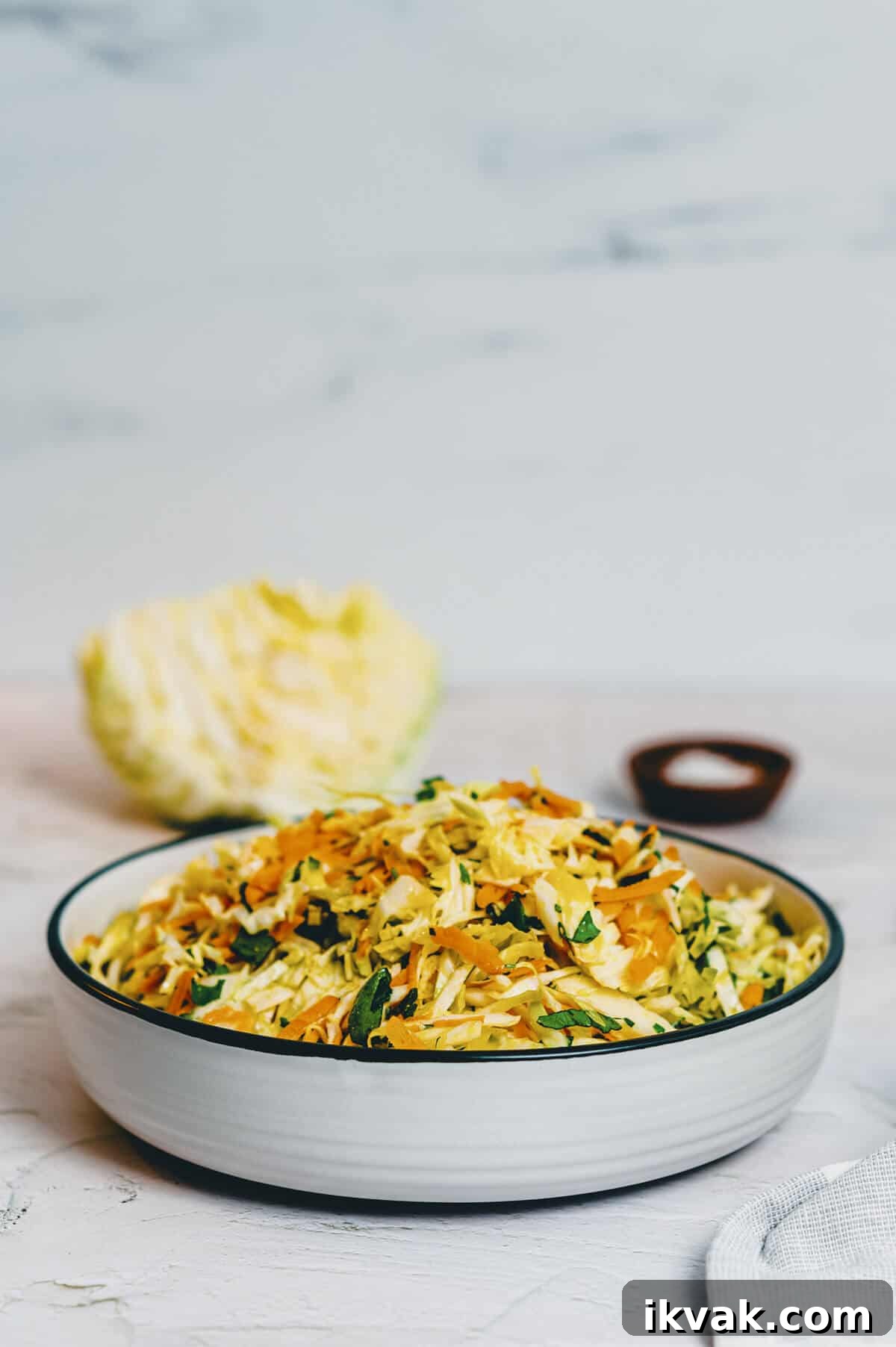 a bowl of cabbage salad on a white surface.