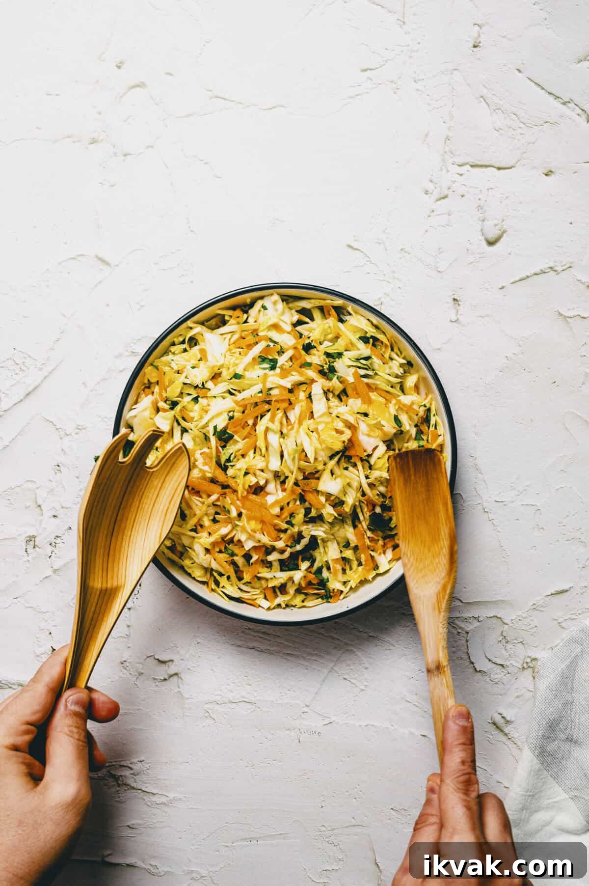 a salad being tossed in a bowl on a white surface.