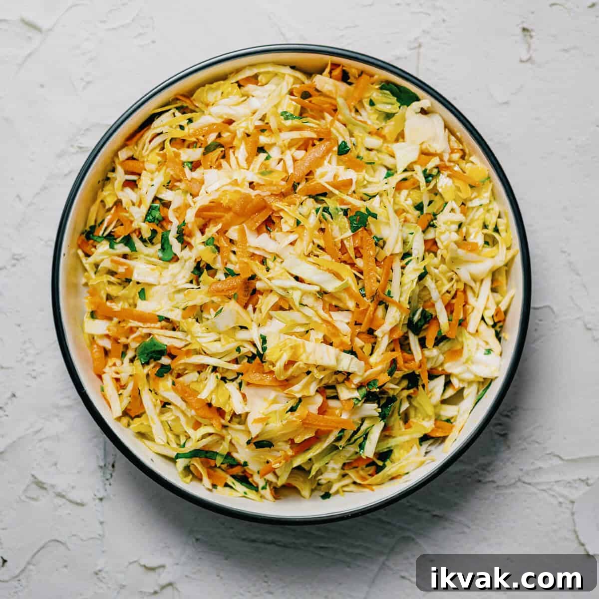 a bowl of Greek cabbage salad on a white surface.
