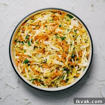 a bowl of Greek cabbage salad on a white surface.