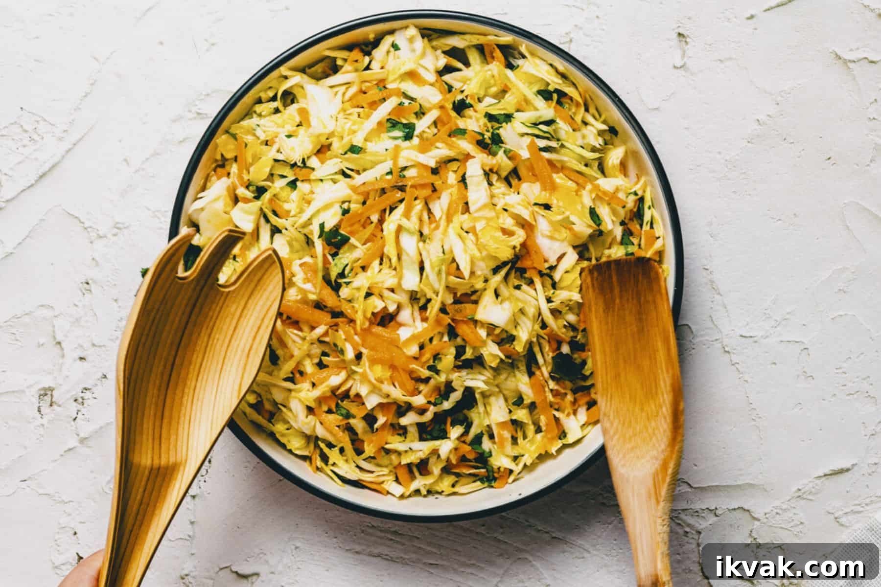 a Greek cabbage salad being tossed in a bowl.