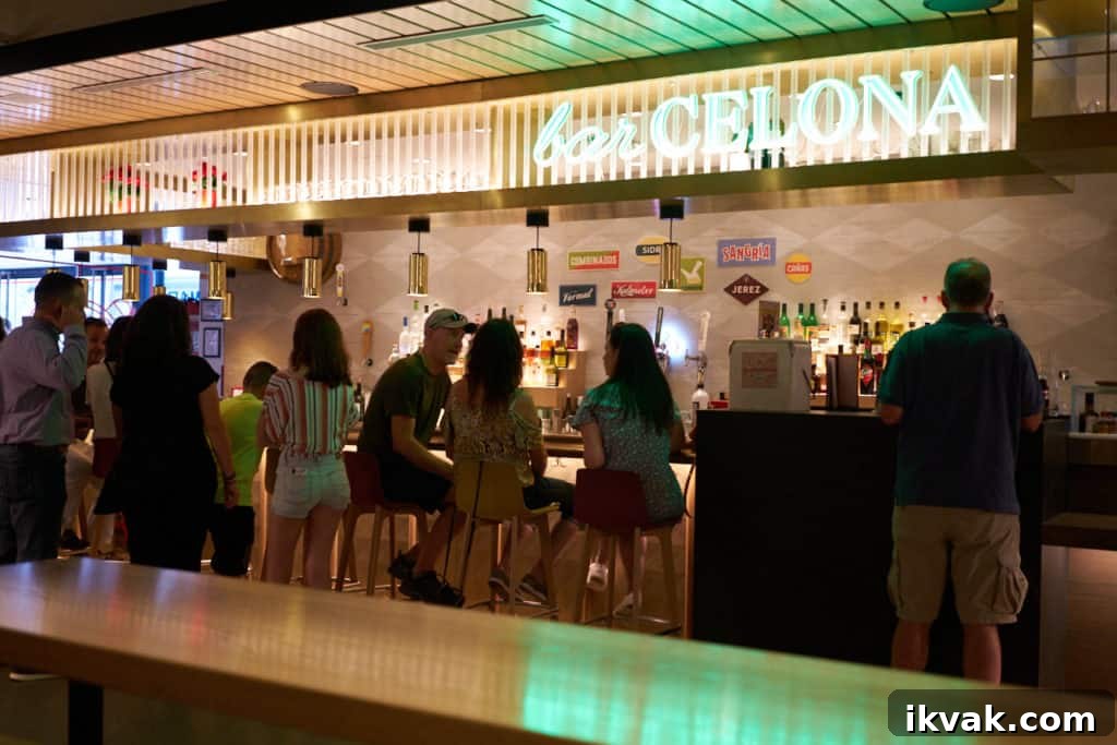 People at a bar with a green neon sign over it that reads, "barCELONA".