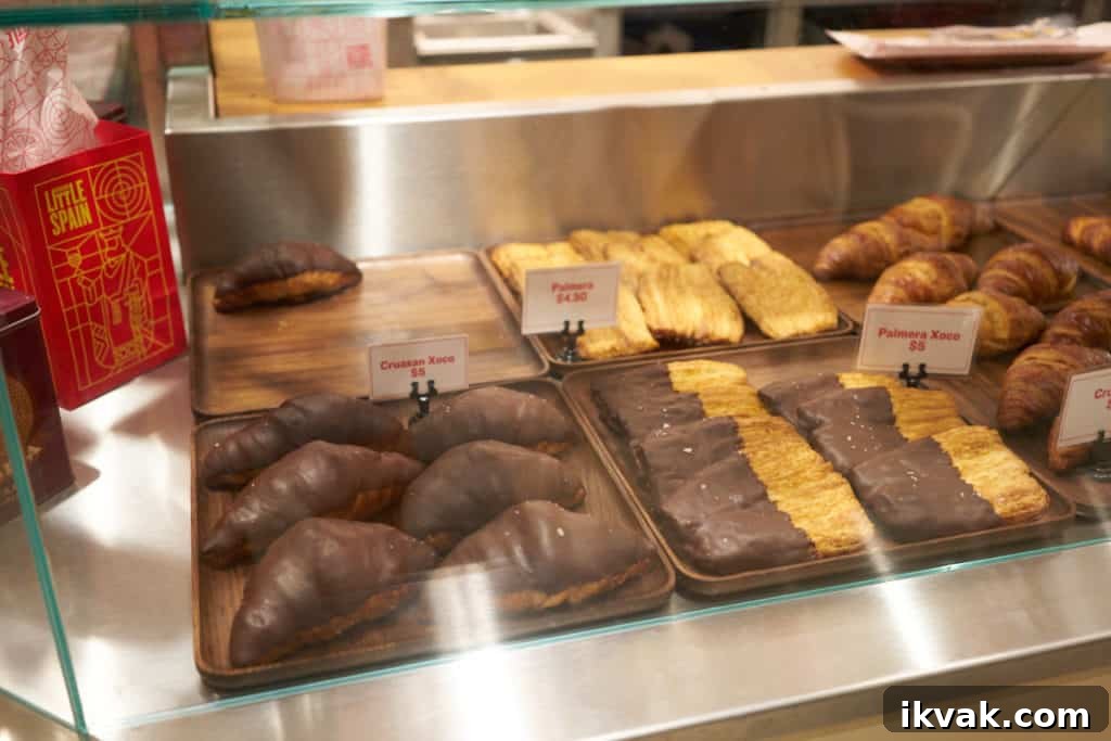 Chocolate covered croissants and other baked goods in a bakery case. 