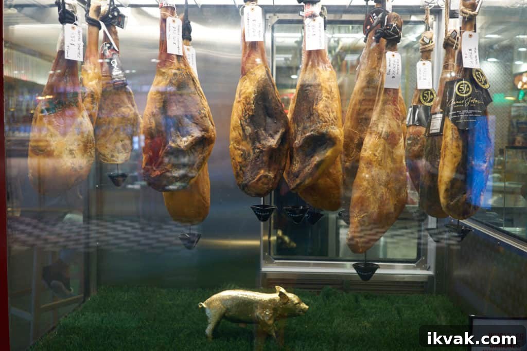 Spanish hams hanging in a case with a decorative gold pig below them.