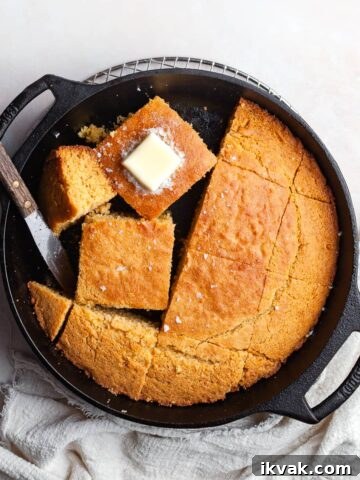 a sliced gluten free cornbread baked in a skillet, topped with melted butter and flaky sea salt, gluten free skillet cornrbread