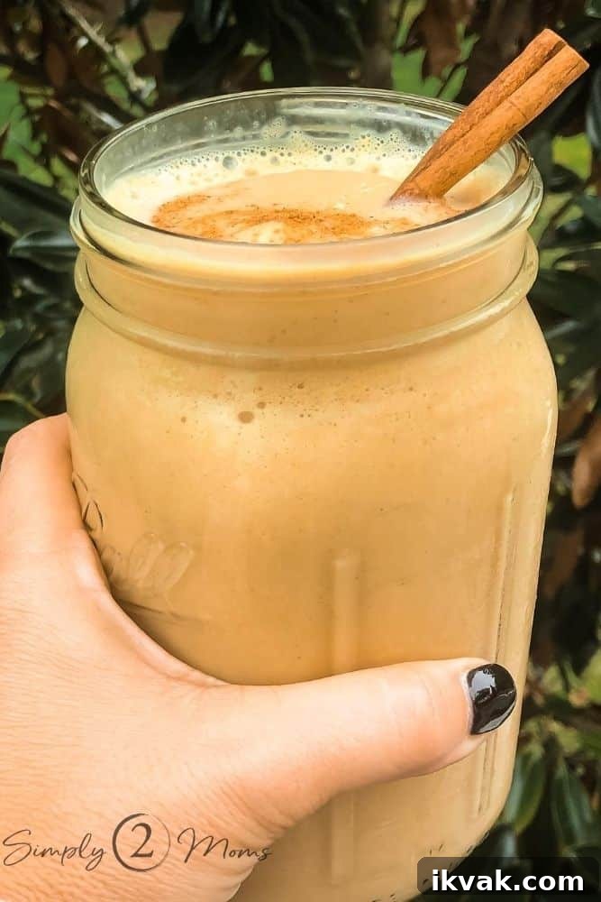 Woman's hand holding a large, wide-mouthed mason jar filled with a pumpkin spice latte custard shake.
