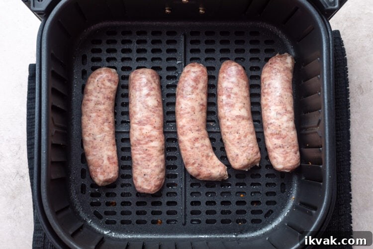 5 uncooked Italian sausage links in an air fryer basket.