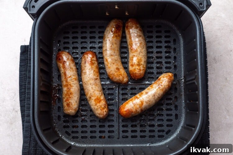 5 cooked Italian sausages in an air fryer basket.