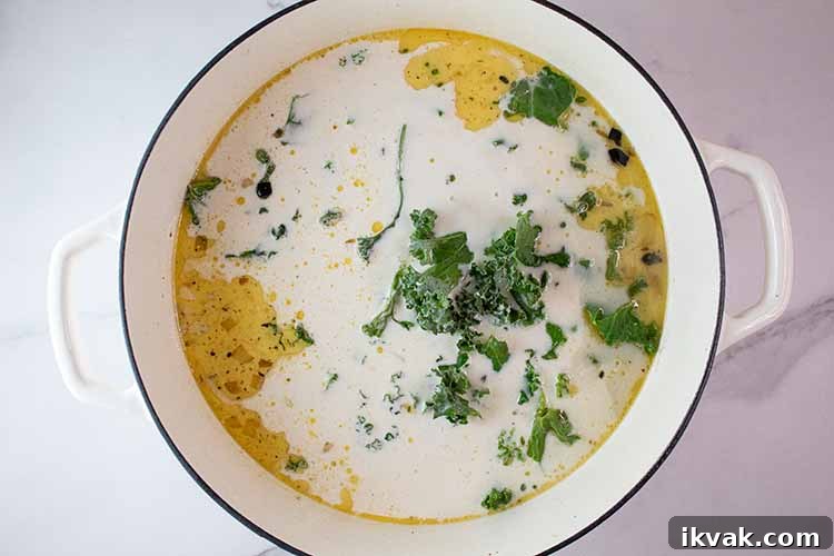 overhead view of ceramic soup pot with chicken stock, heavy whipping cream and kale added