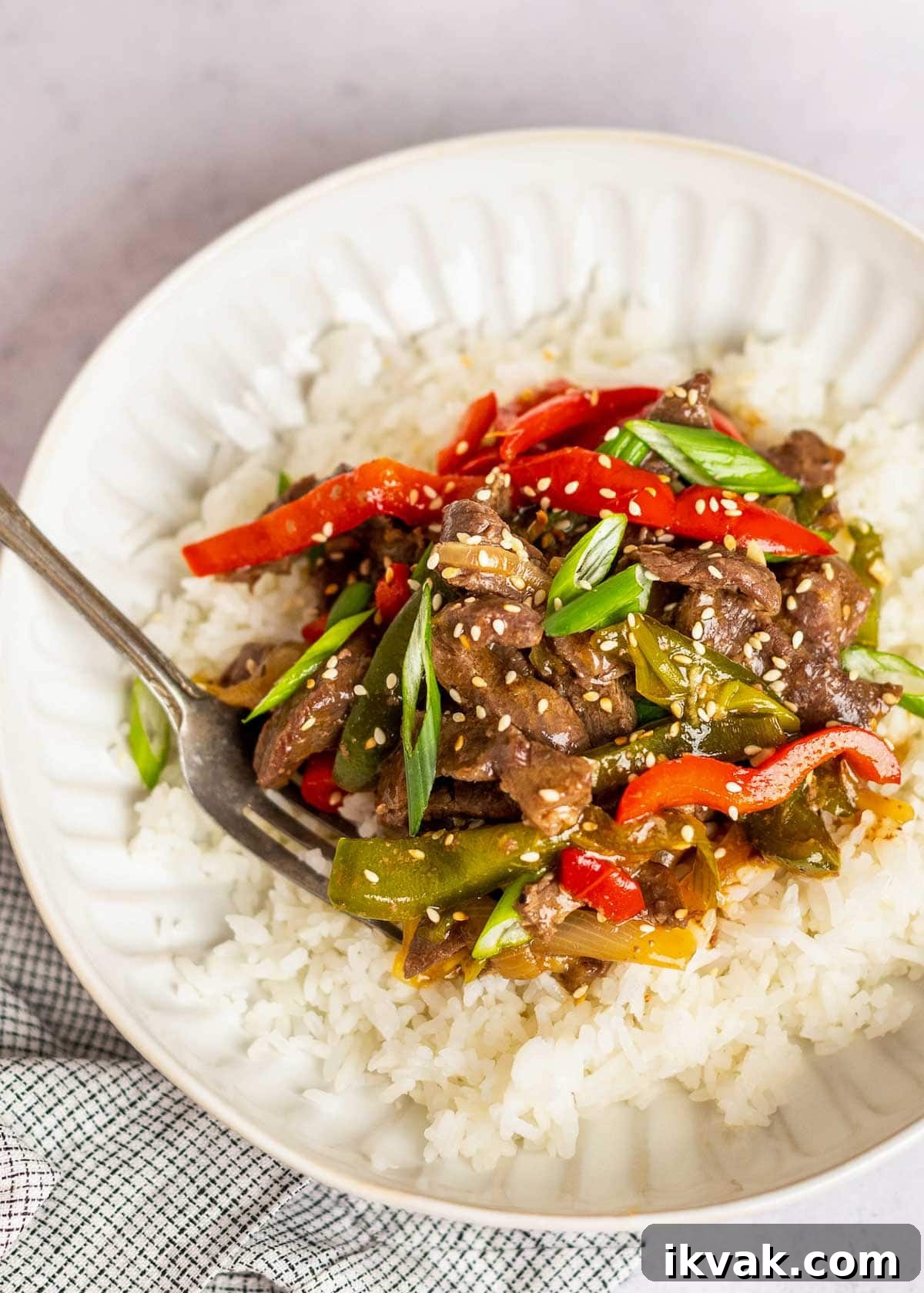 pepper steak on plate with rice and fork.