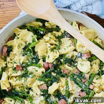 pan with a wodden spoon and tortellini pasta with ham and asparagus
