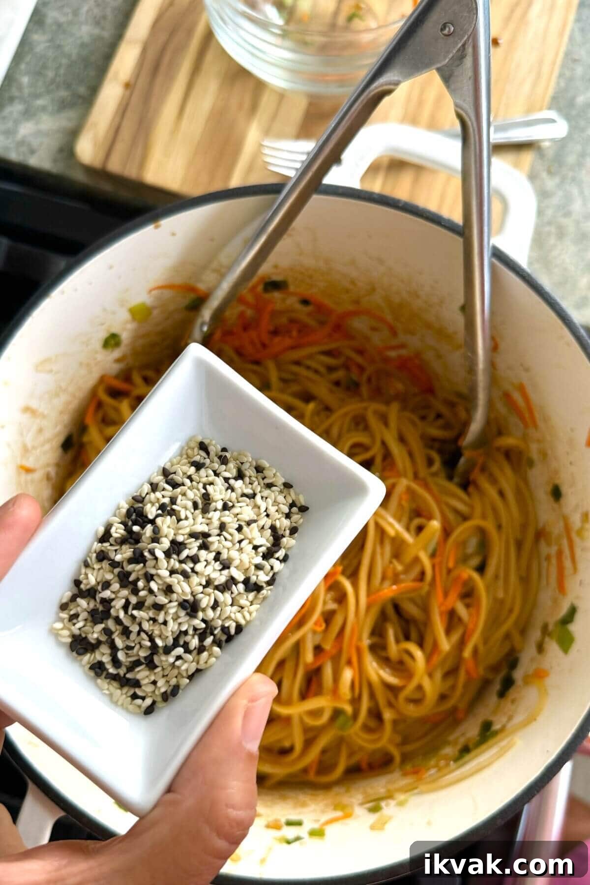 adding sesame seeds to noodles.
