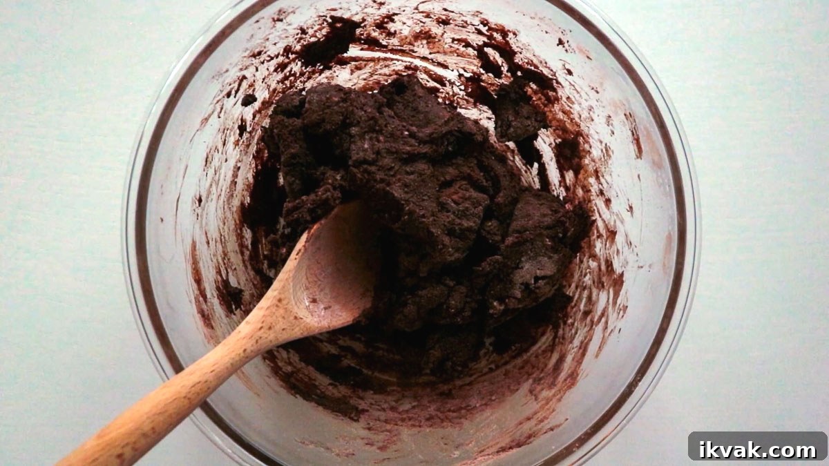 Cookie dough in a glass bowl with wooden spoon.