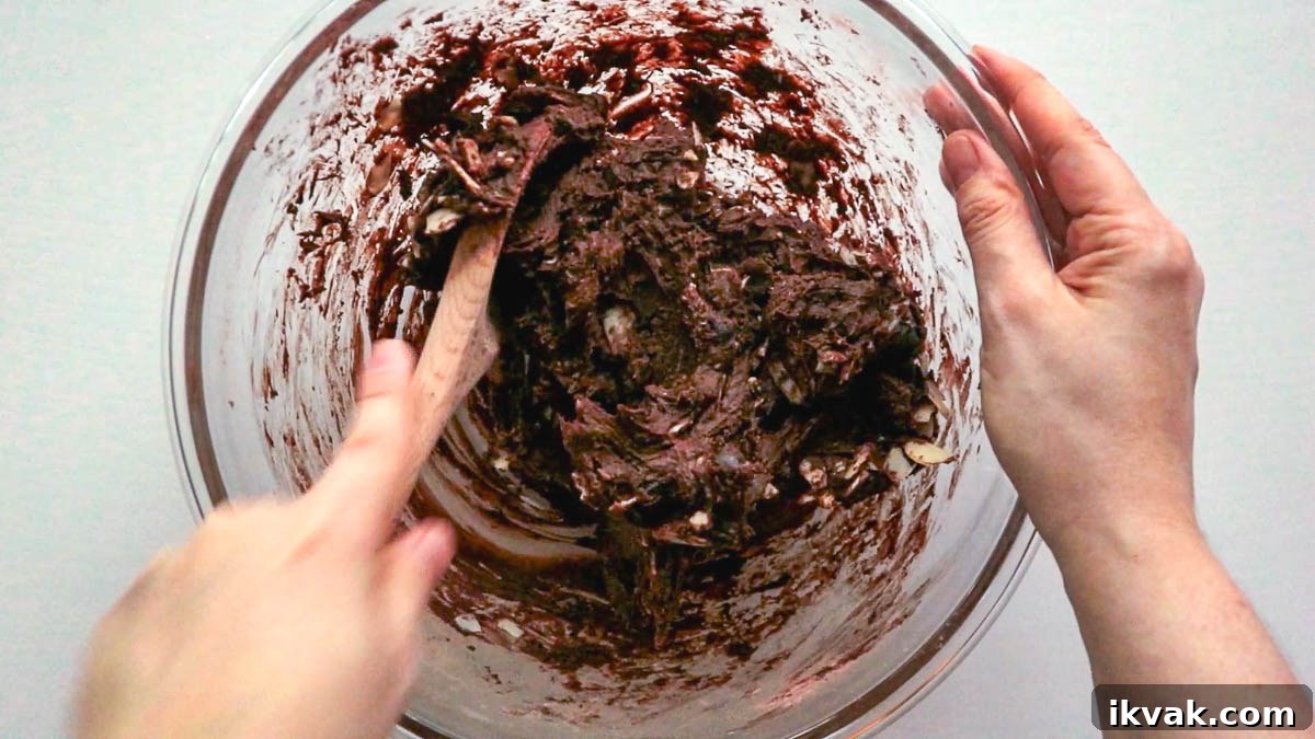Hand using spoon to mix cookie dough.