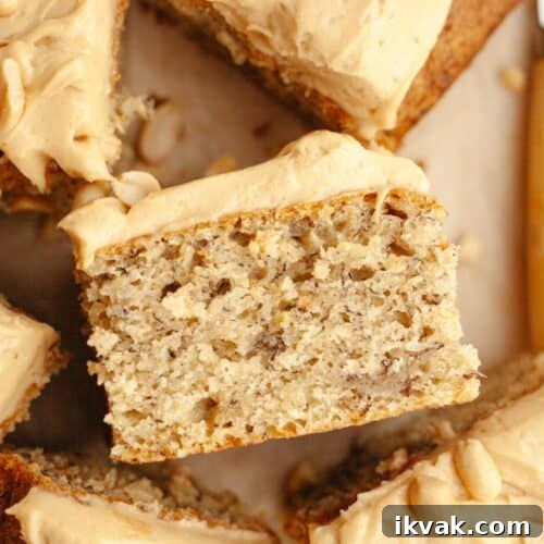 A close up of a slice of banana cake with peanut butter frosting, on it's side.