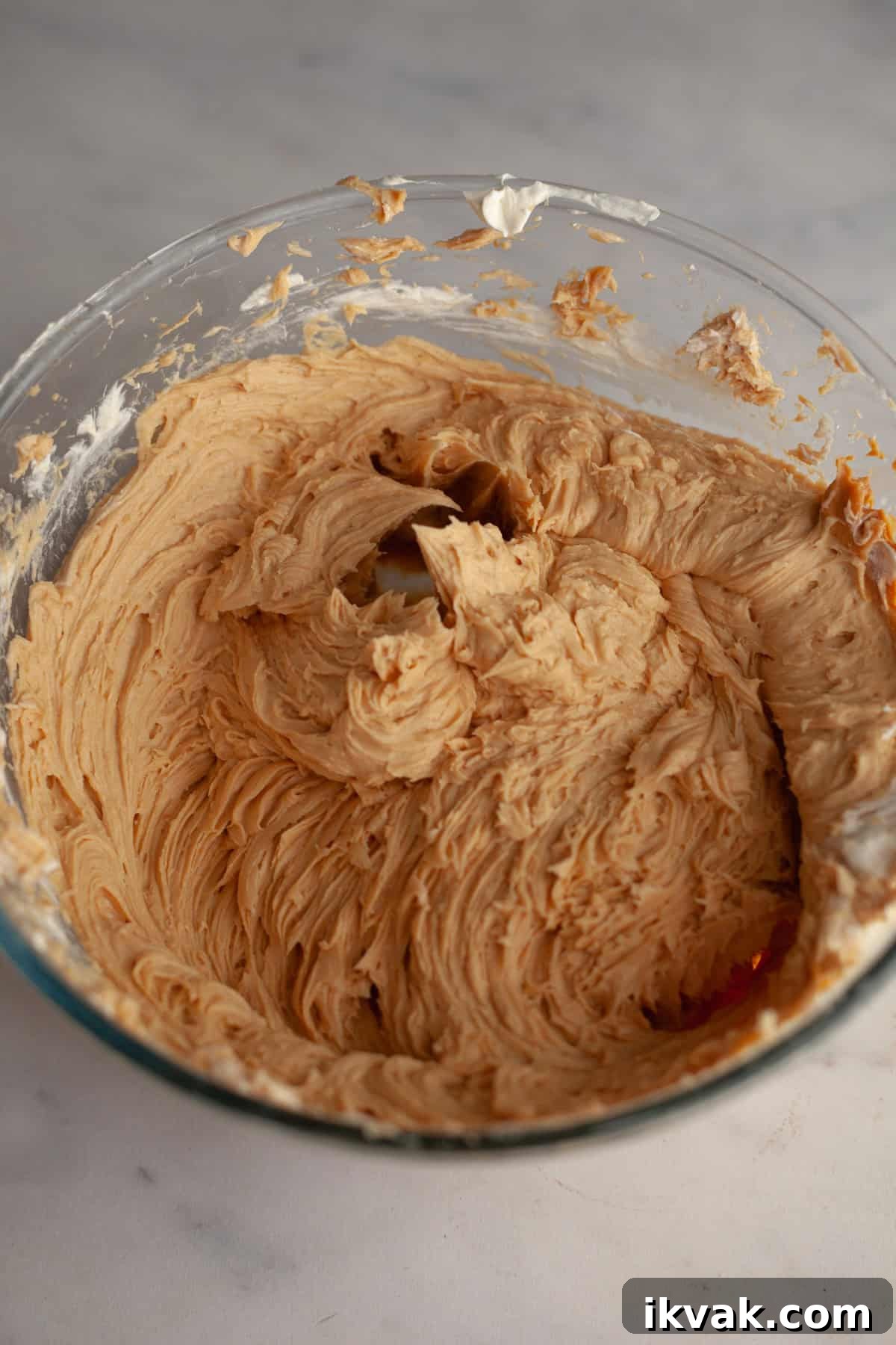 A large glass bowl with peanut butter frosting in it.
