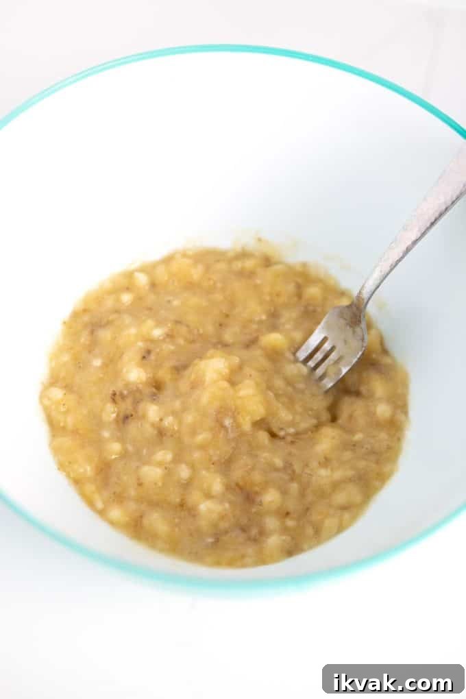 Mashing ripe bananas with fork in bowl