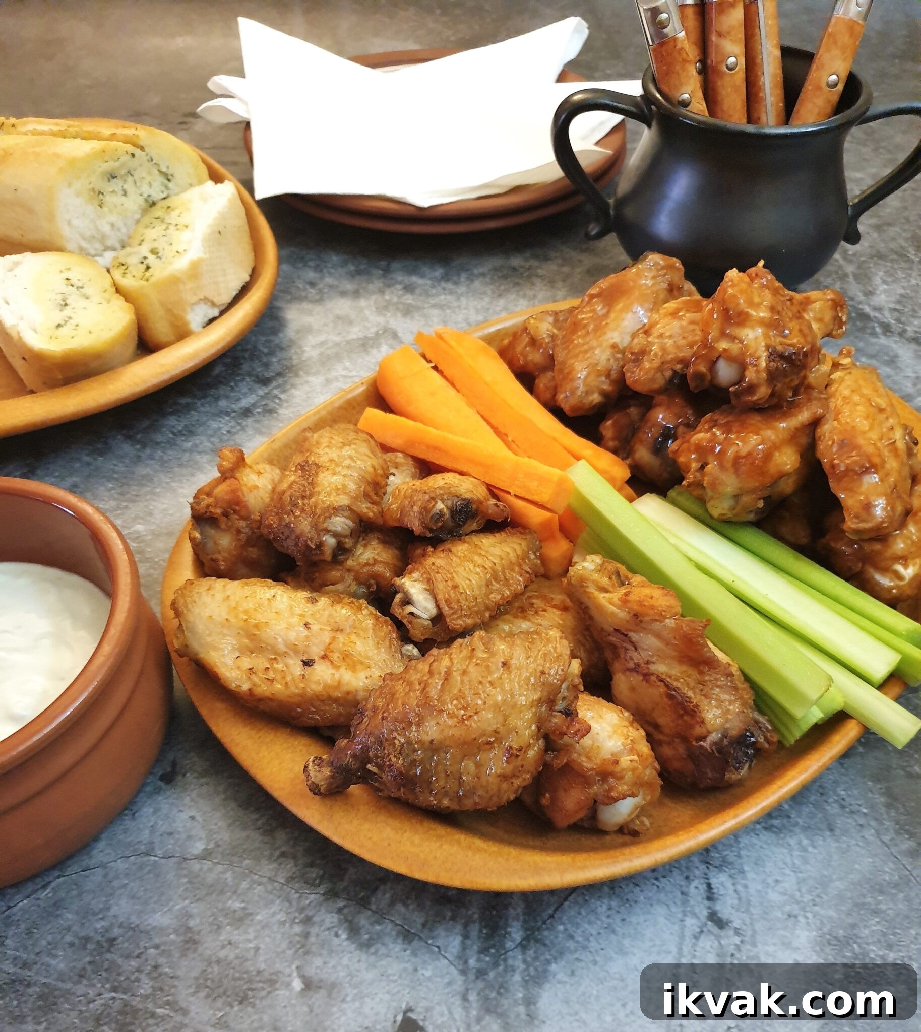 A plate of crispy air-fryer crispy chicken wings on a table with carrot and celery sticks.