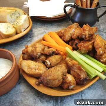 A plate of crispy air-fryer crispy chicken wings on a table with carrot and celery sticks.