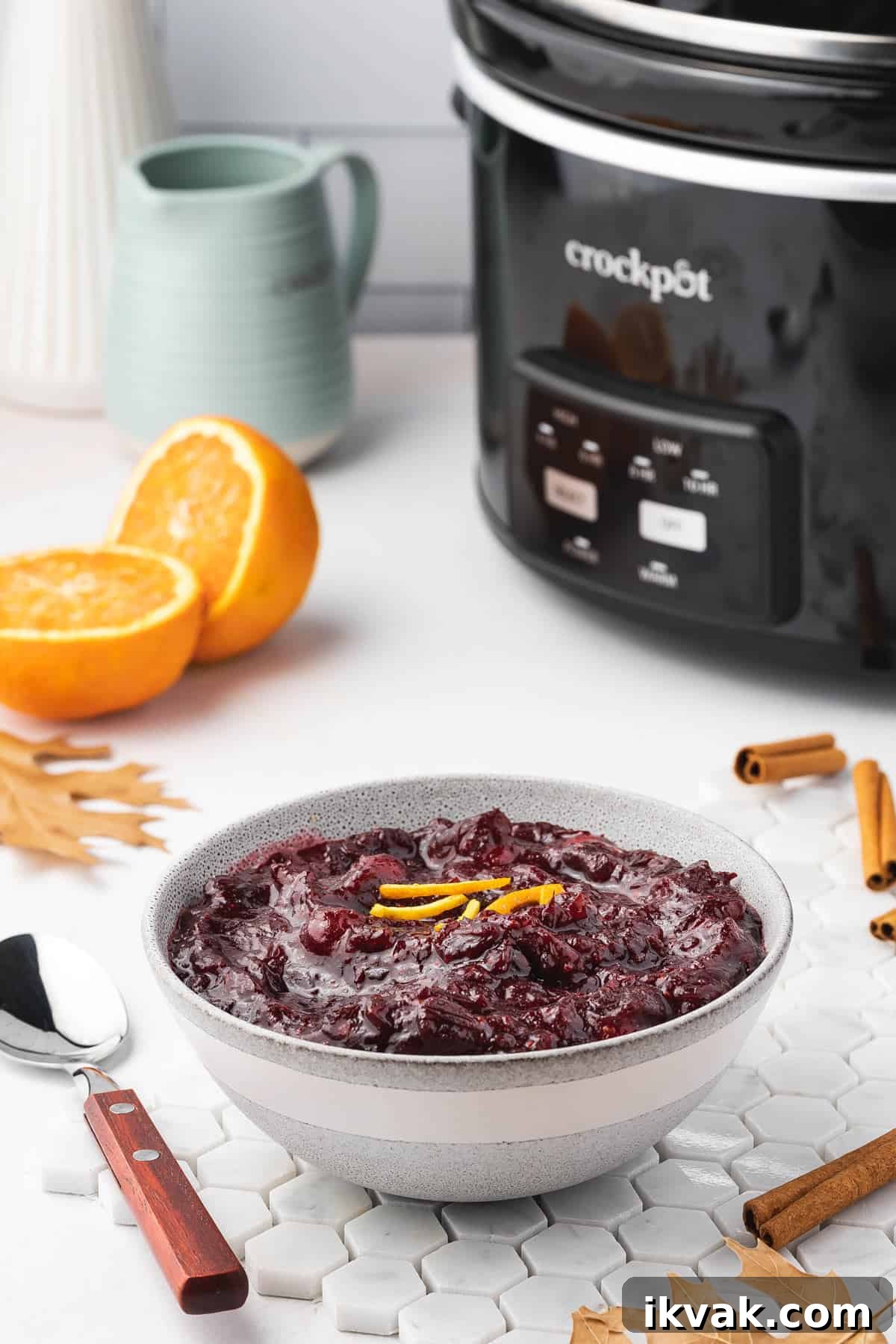 A bowl of cranberry sauce with a crockpot in the background.