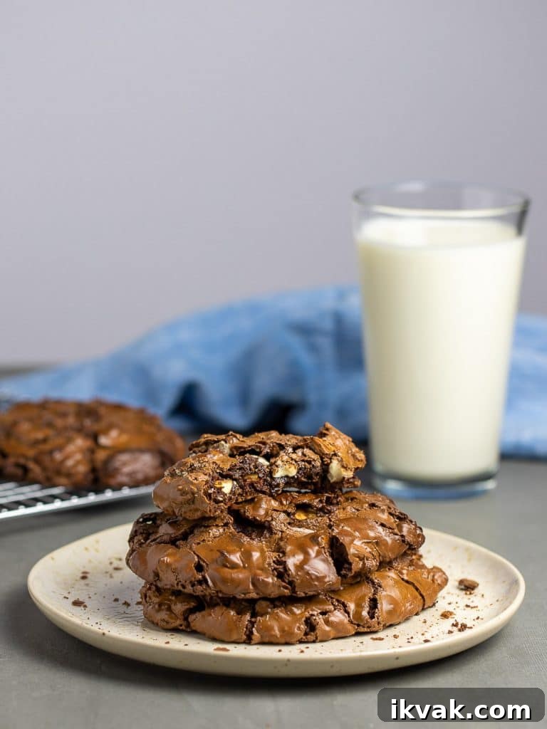 chocolate cookies stacked on plate in front of glass of milk and blue napkin