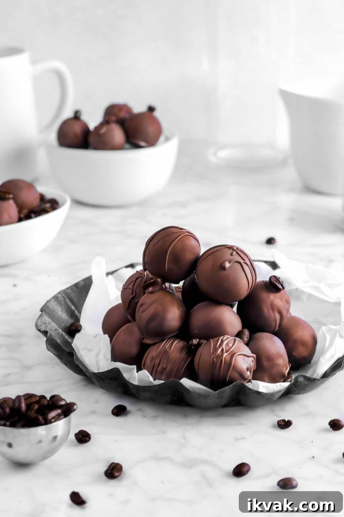 stacked coffee truffles on lined pan with coffee beans and more truffles behind