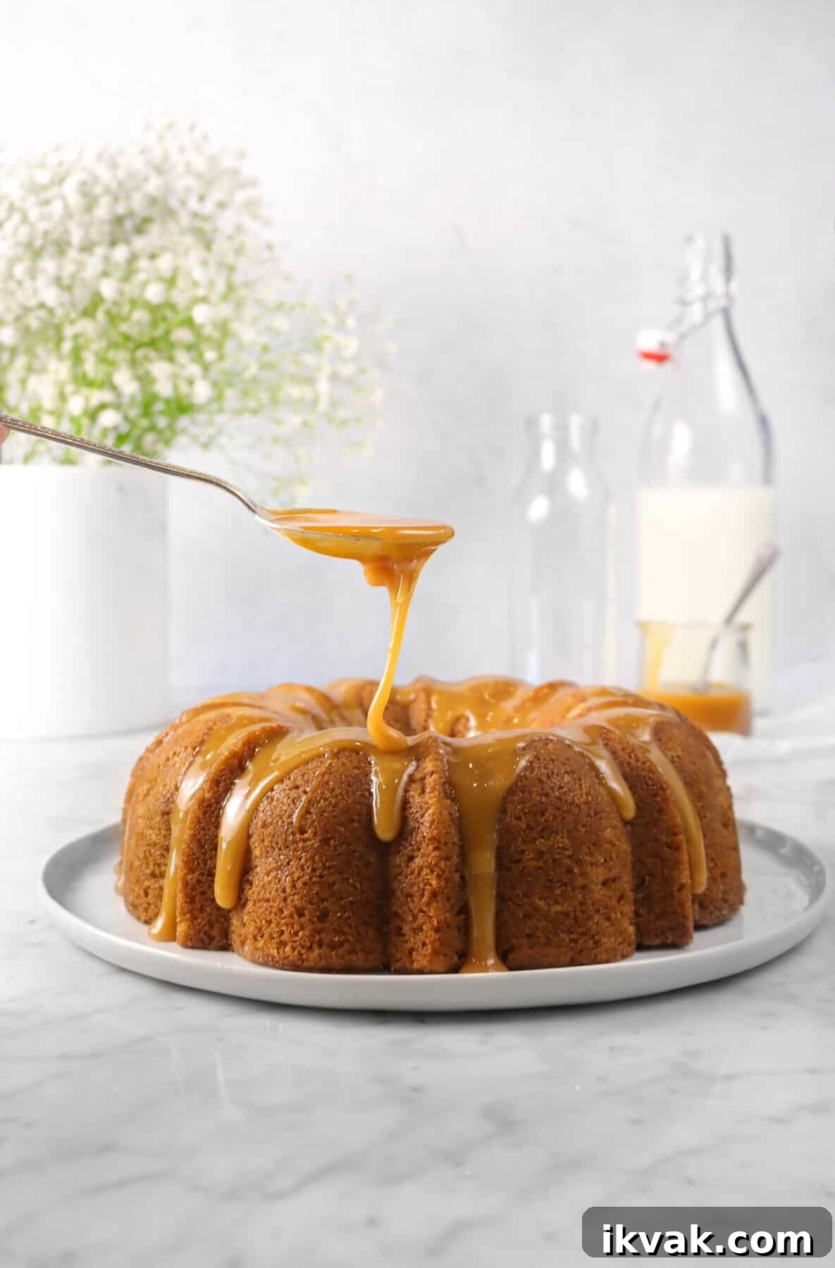 apple cinnamon cake on a white plate with caramel being drizzled onto it