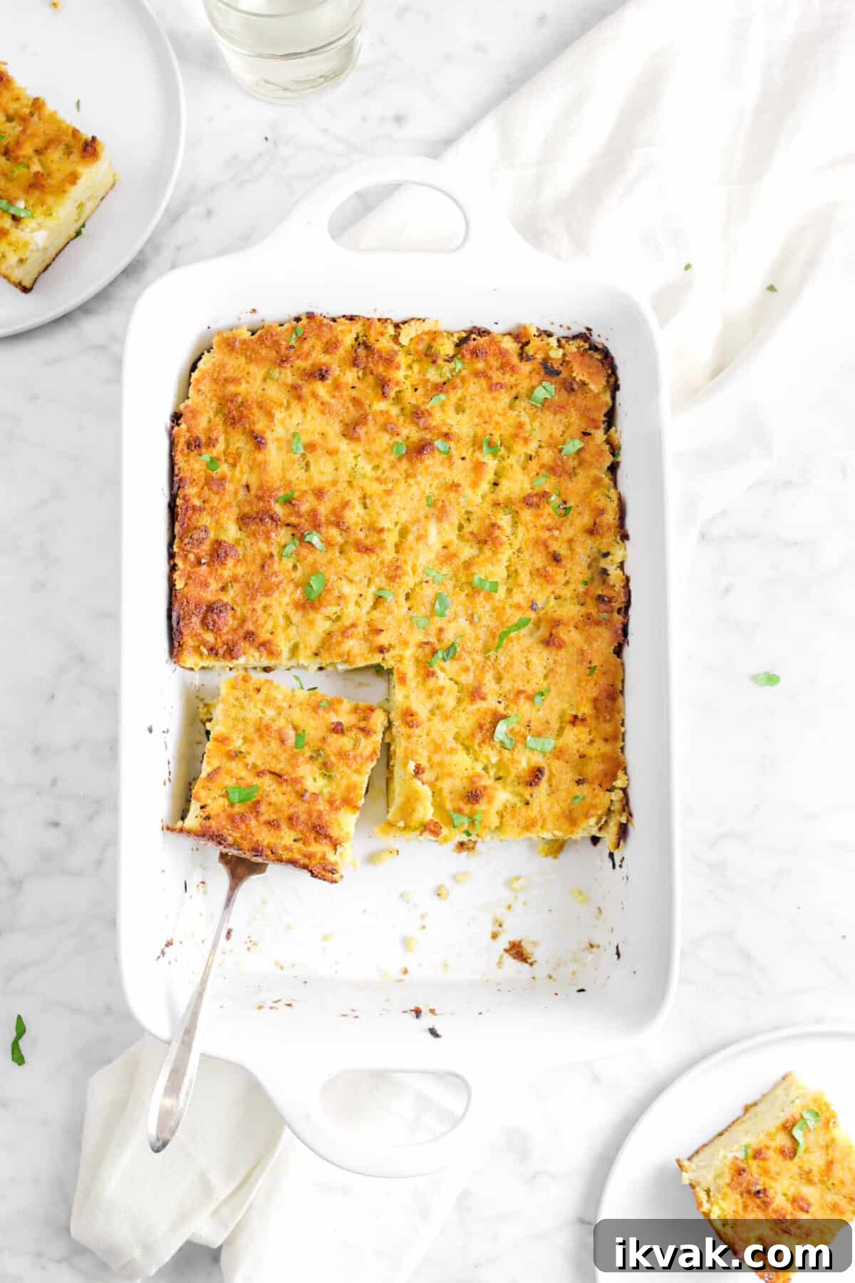 cornbread dressing with a slice sitting in the pan and two plates of dressing