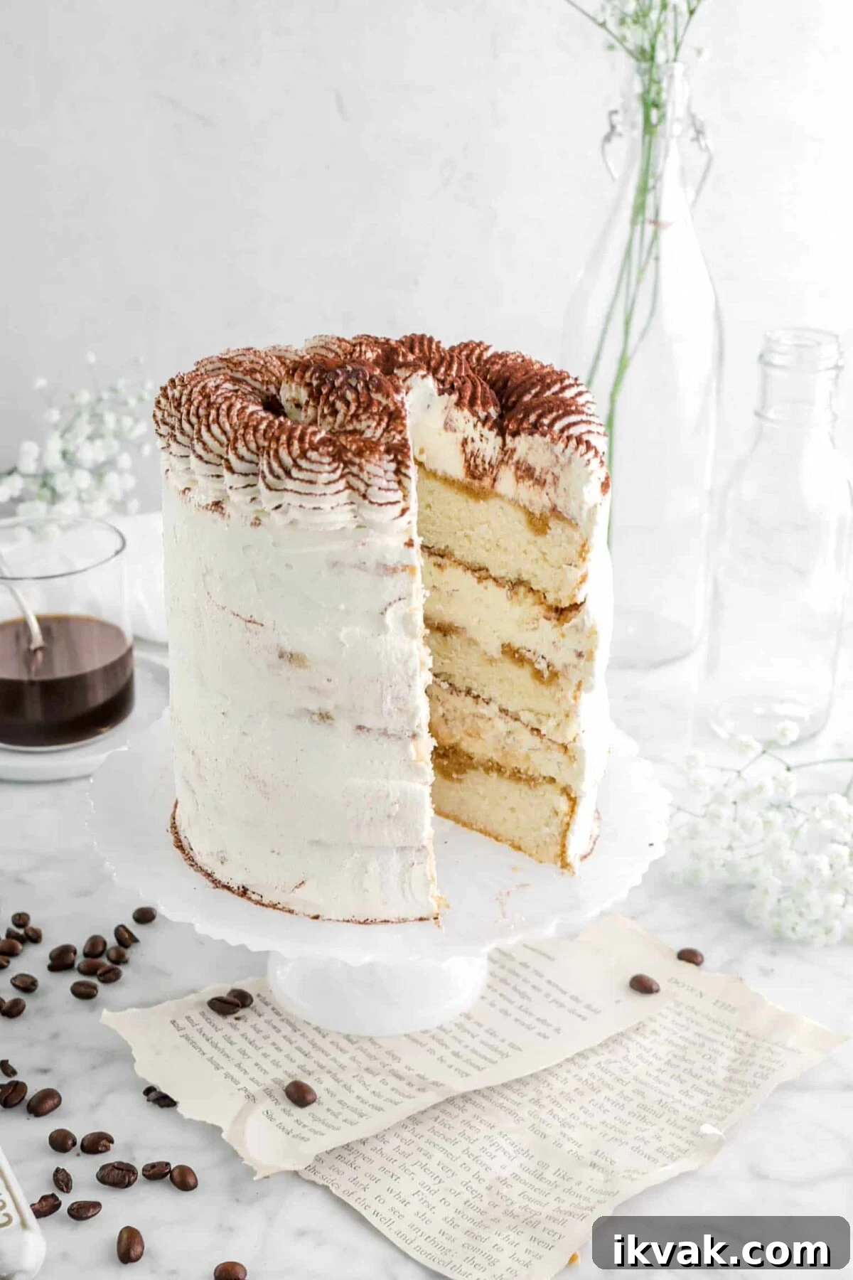 close up of cake with slice missing out of it on white cake stand