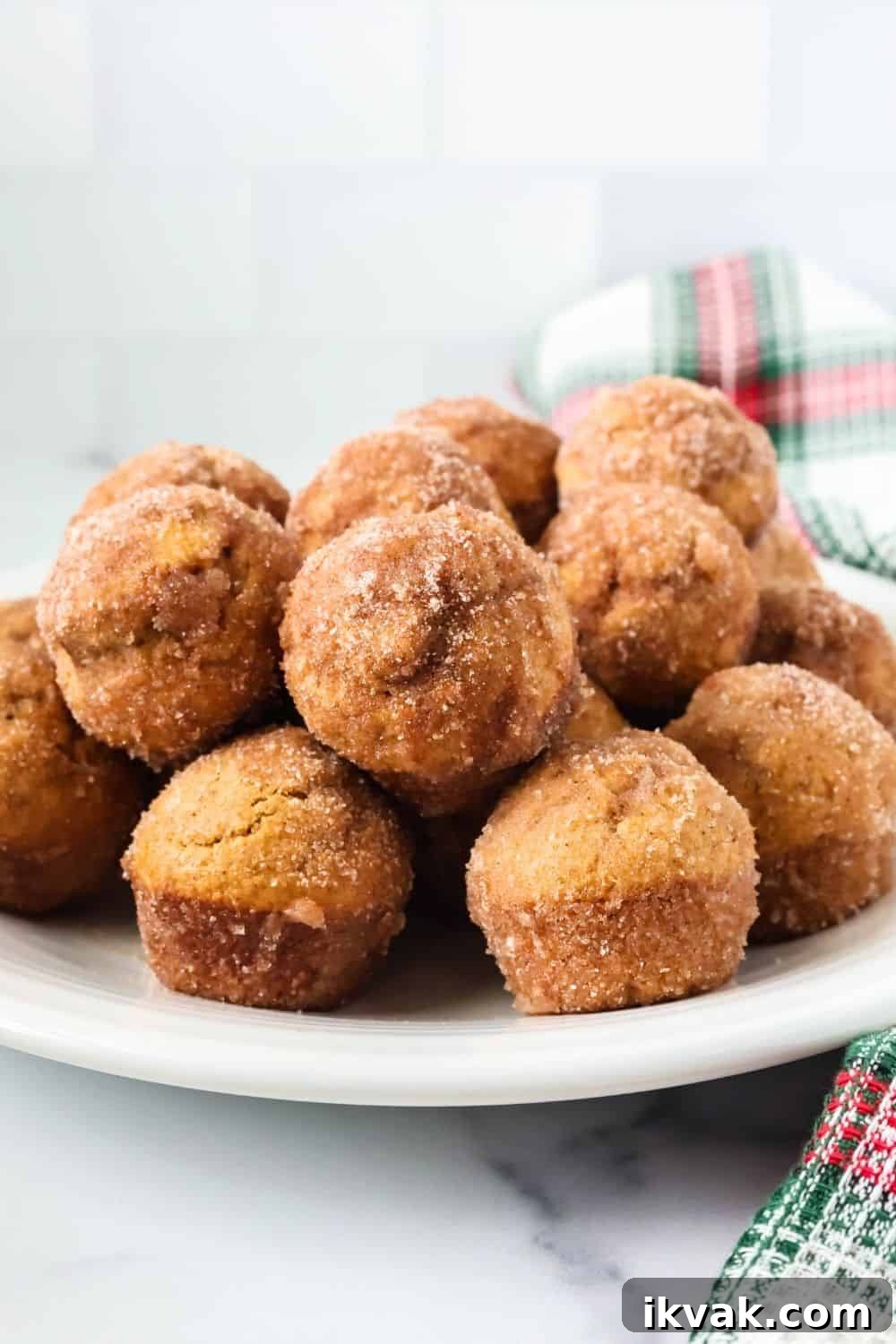 side view of a stack of gingerbread donut bite mini muffins for Christmas, served on a white plate.