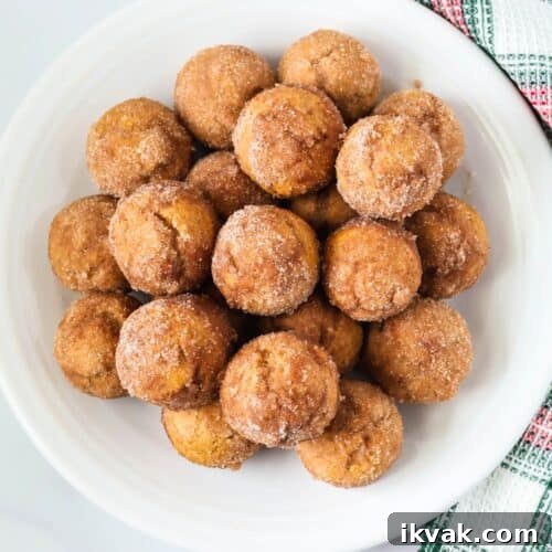 overhead view of Bisquick gingerbread donut holes served on a white plate, with a Christmas plaid kitchen towel next to the plate.