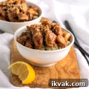 Two bowls of Chinese lemon chicken with sesame seeds and cauliflower rice.