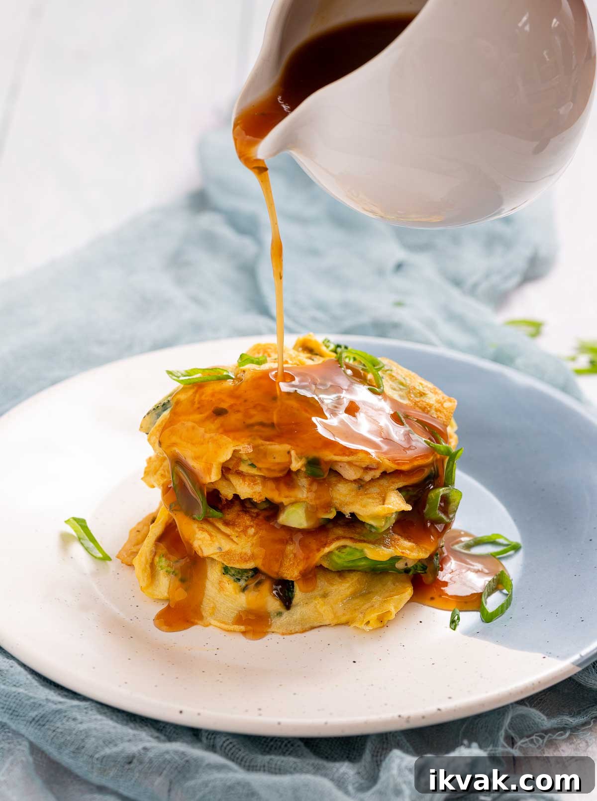 Keto Egg Foo Young Recipe: Low-Carb Chinese-Style Omelette 3 A stack of egg foo young patties with gravy pouring over them.