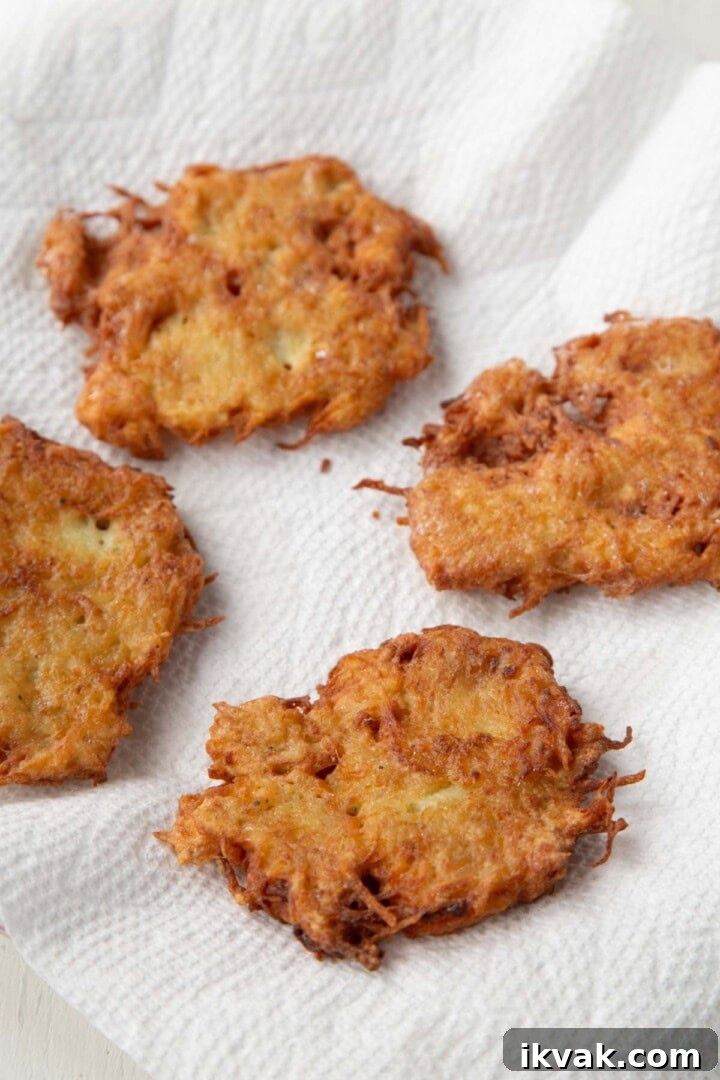 Crispy Potato Pancakes Recipe: Golden Hash Browns from Scratch 11 potato pancakes draining on a paper towel.