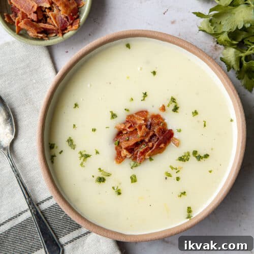 bowl of potato soup topped with chopped bacon and parsley.