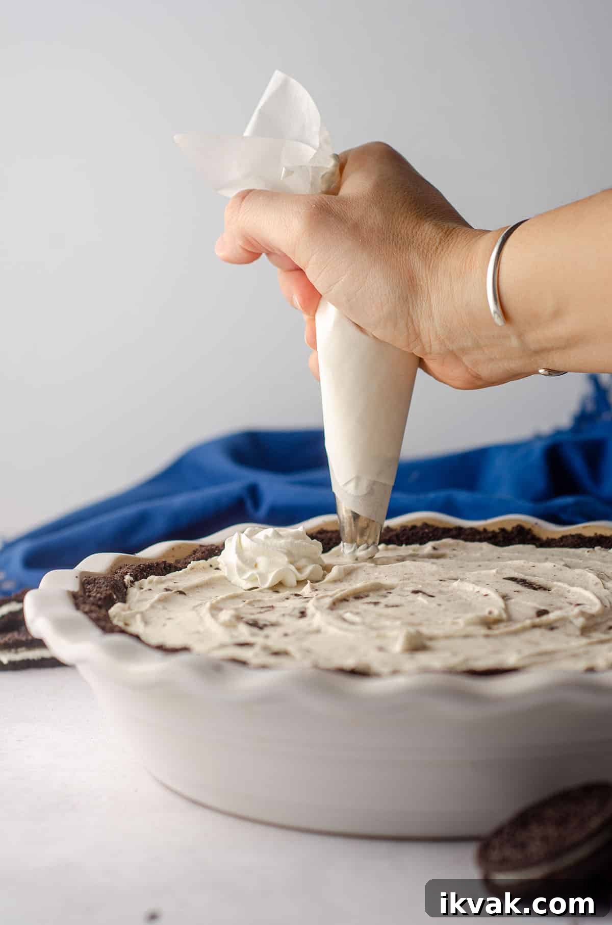 hand piping homemade whipped cream onto the top of no bake oreo pie