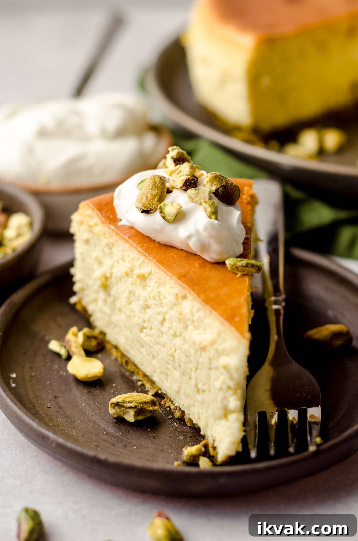 slice of pistachio cheesecake with a dollop of homemade whipped cream on top