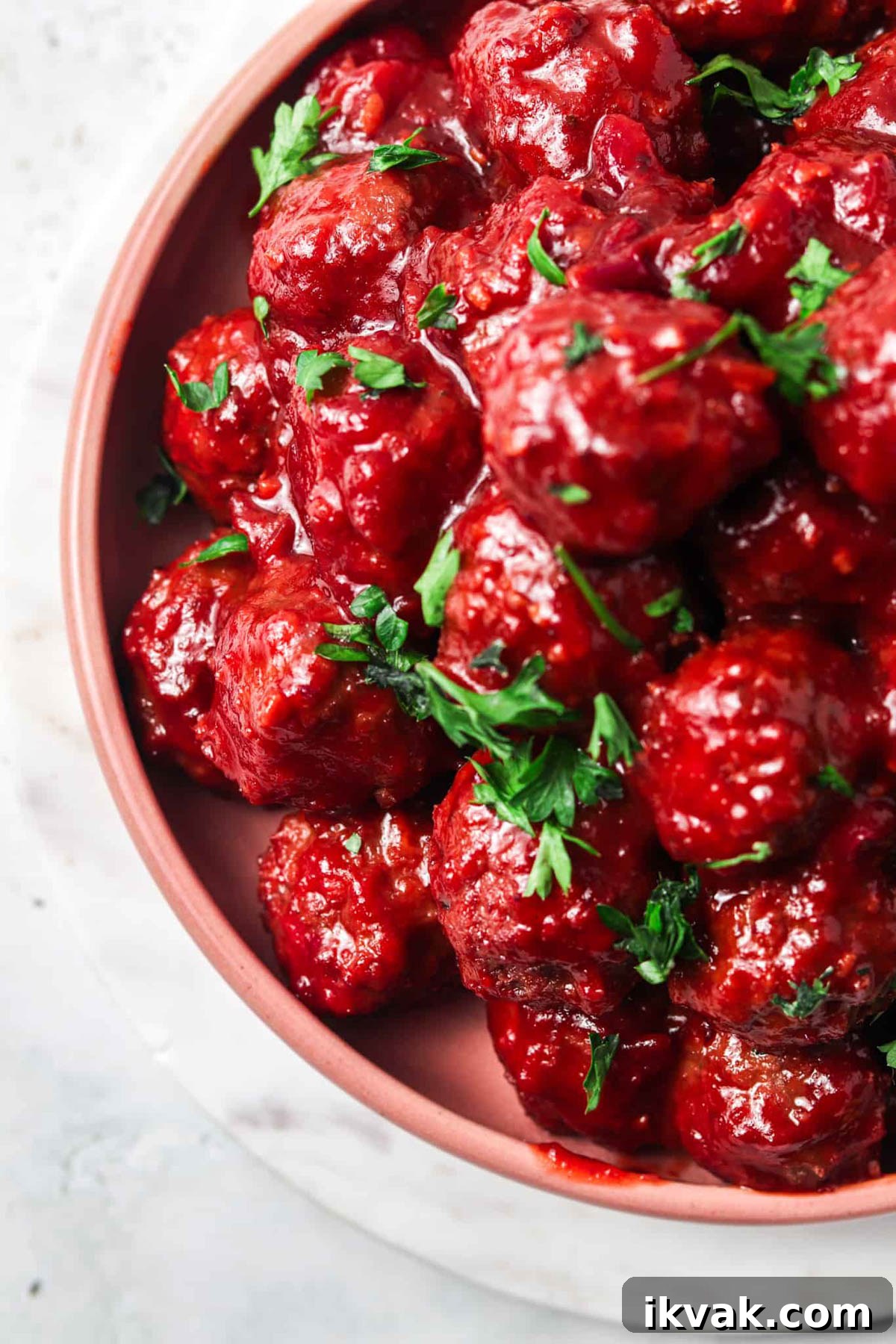 Sweet Cranberry BBQ Meatballs for Parties and Weeknights 5 Cranberry BBQ Meatballs on a pink plate and garnished with fresh herbs.
