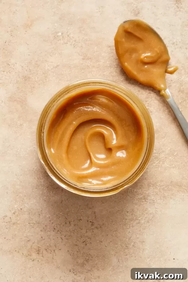 A jar of Non Dairy Caramel Sauce with some to the side in a spoon.