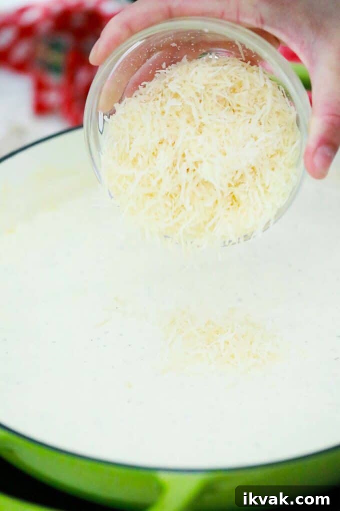 Creamy Homemade Alfredo Sauce Recipe for Pasta Night 7 adding parmesan cheese to homemade Alfredo sauce
