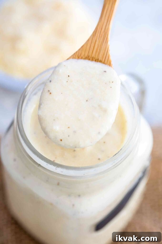 Creamy Homemade Alfredo Sauce Recipe for Pasta Night 9 Alfredo Sauce on a wooden spoon on top of a jar with sauce
