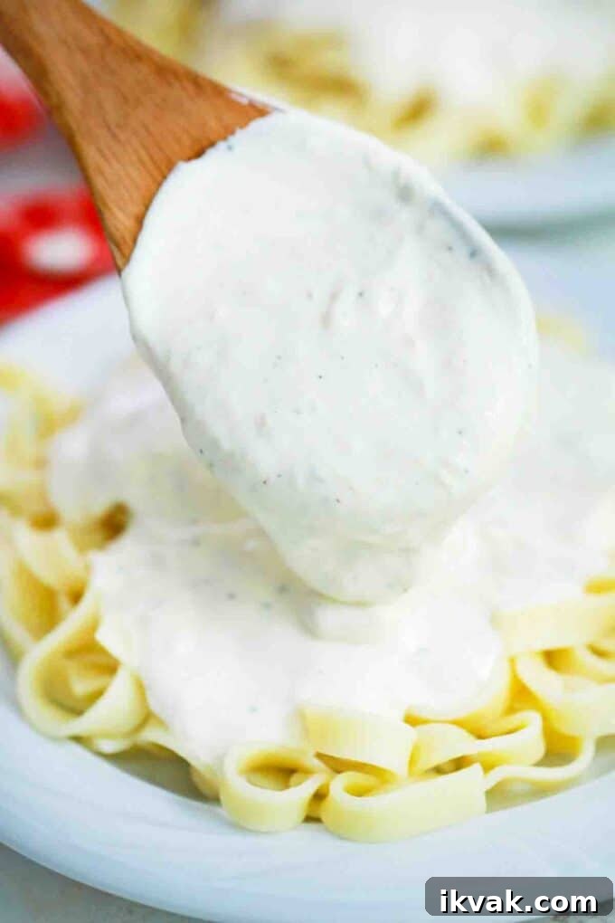 Creamy Homemade Alfredo Sauce Recipe for Pasta Night 10 pouring Alfredo sauce over fettuccine pasta