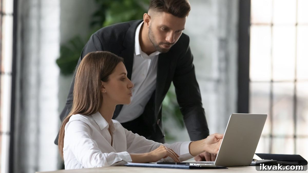 man helping woman on computer at work