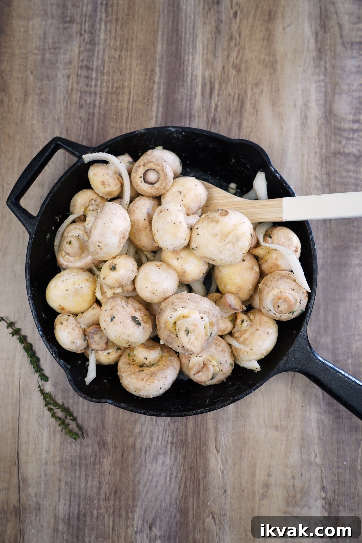 Mushrooms tossed with ingredients in cast iron skillet.