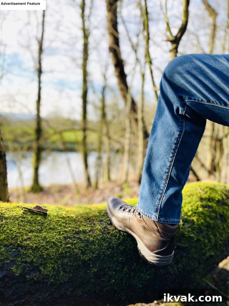 mens waterproof walking boots from Go Outdoors in brown - man with foot up on fallen tree trunk looking out over lake and forest 