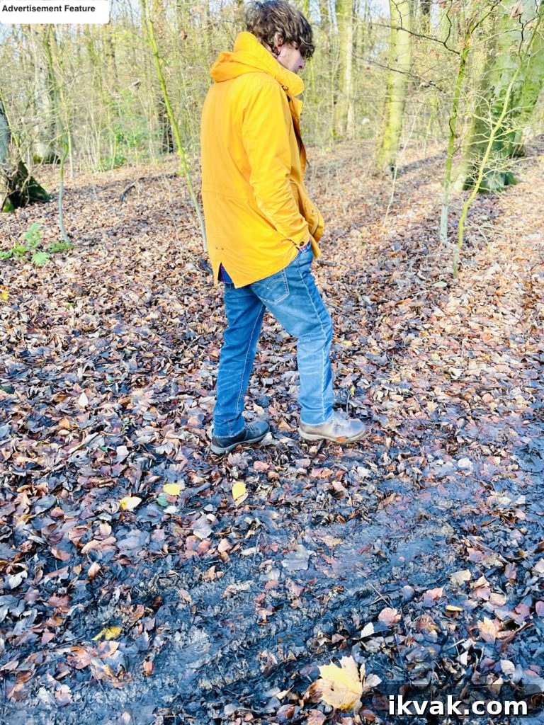 man in yellow coat and mens waterproof walking boots from Go Outdoors in brown walking through forest 