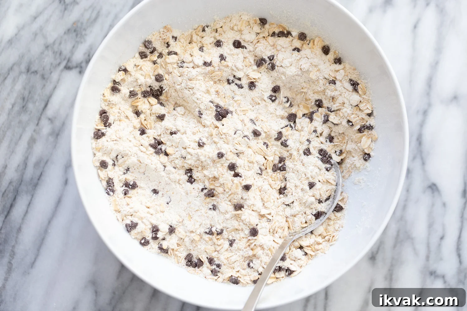 dry ingredients for vegan oatmeal chocolate chip waffles being stirred in a white bowl
