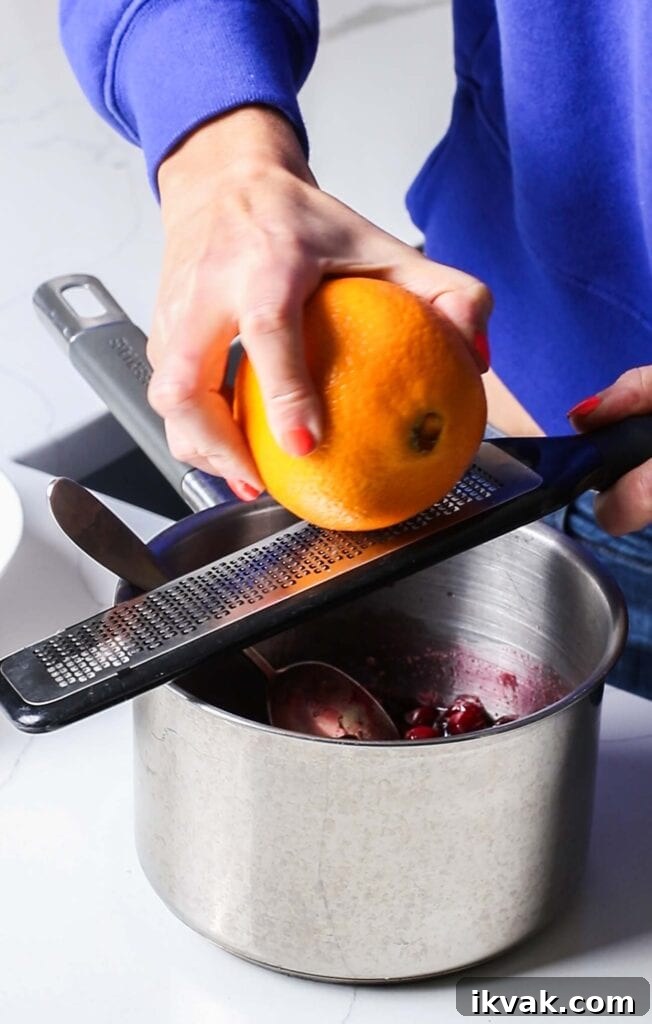 Maple Cranberry Sauce Recipe: Sweet-Tart Holiday Condiment 5 Grating orange zest into a pan of cranberry sauce.