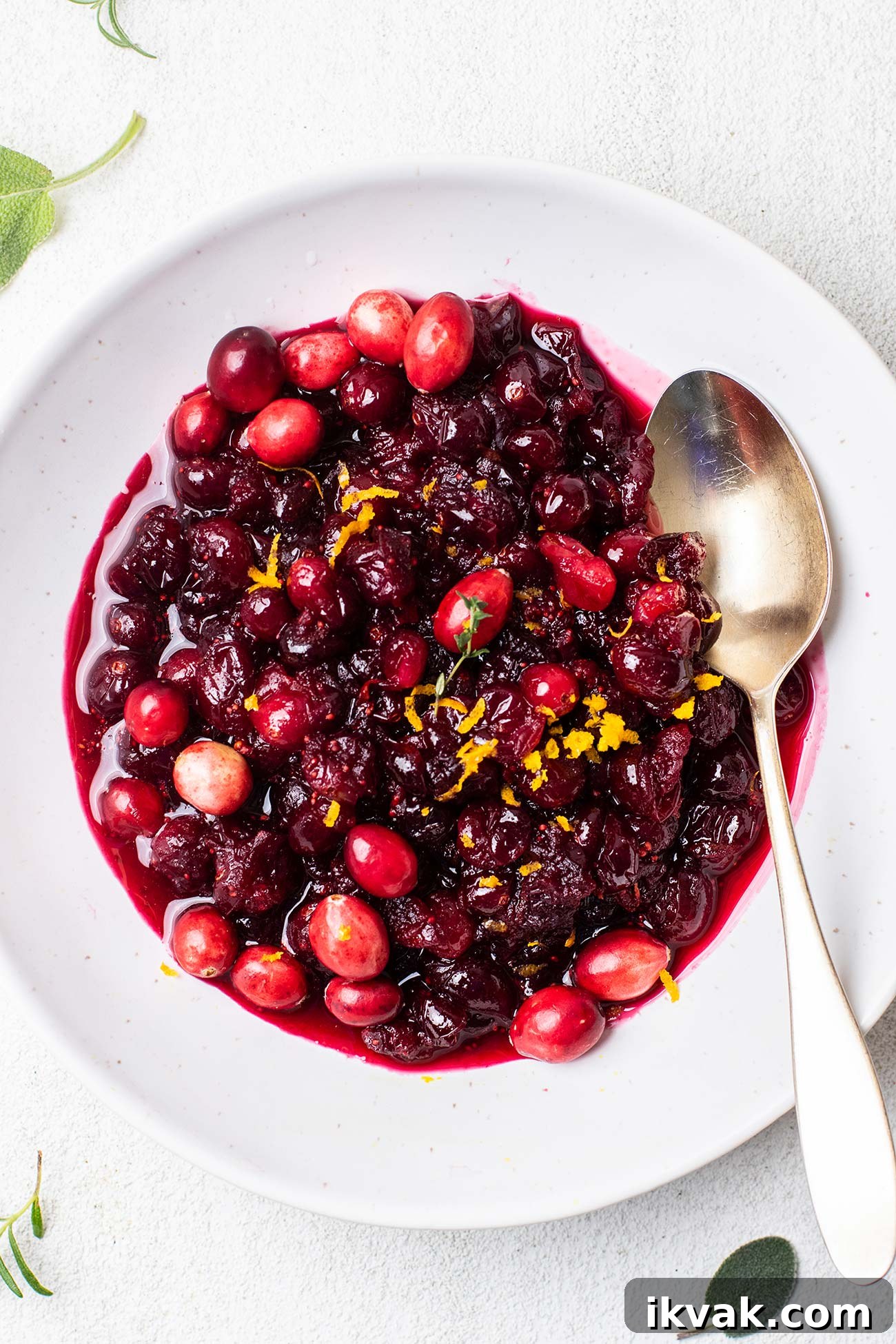 Maple Cranberry Sauce Recipe: Sweet-Tart Holiday Condiment 6 A bowl of cranberry sauce garnished with fresh thyme.